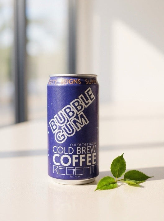 Purple aluminum can with white text on a sunny white table next to a cherry leaf stem