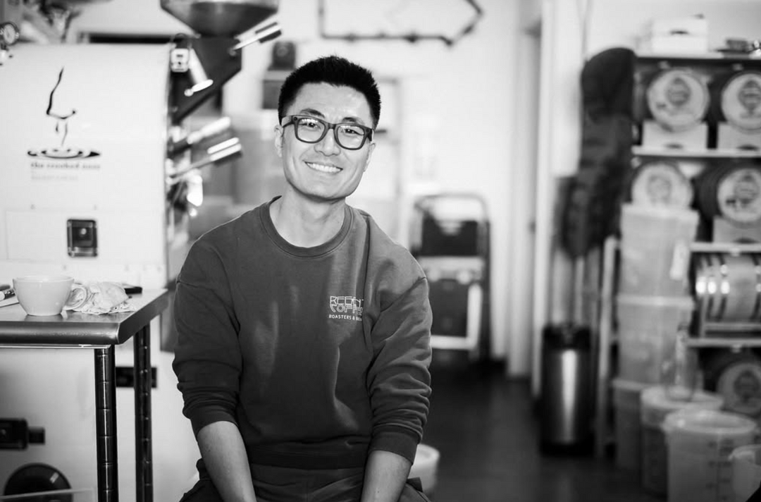 Leon, regent owner, wearing a sweatshirt with text in front of the roasting machine