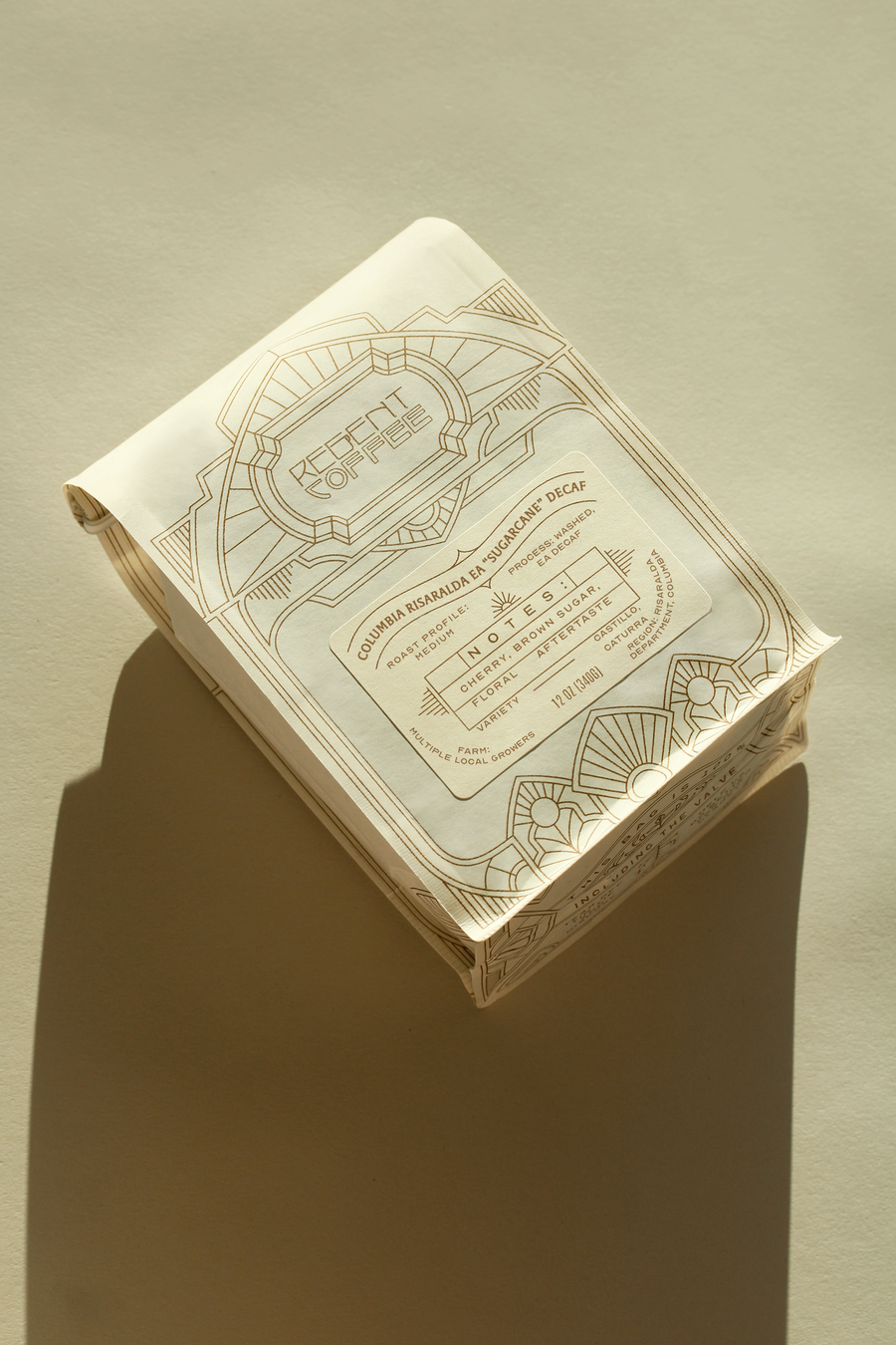 12 oz bag of Colombia Risaralda EA "Sugarcane" Decaf on a cream colored surface casting a single shadow below it