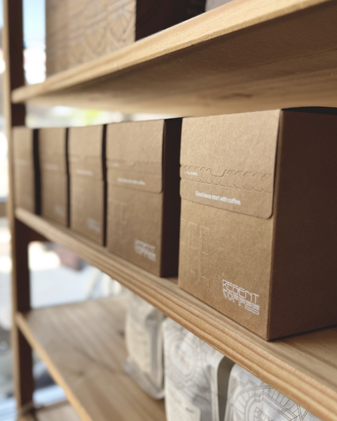 Row of brown boxes with 'Regent Coffee' branding on a wooden shelf.