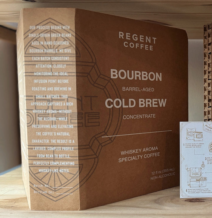 Regent Coffee Bourbon Barrel-Aged Cold Brew concentrate packaging on a wooden surface.