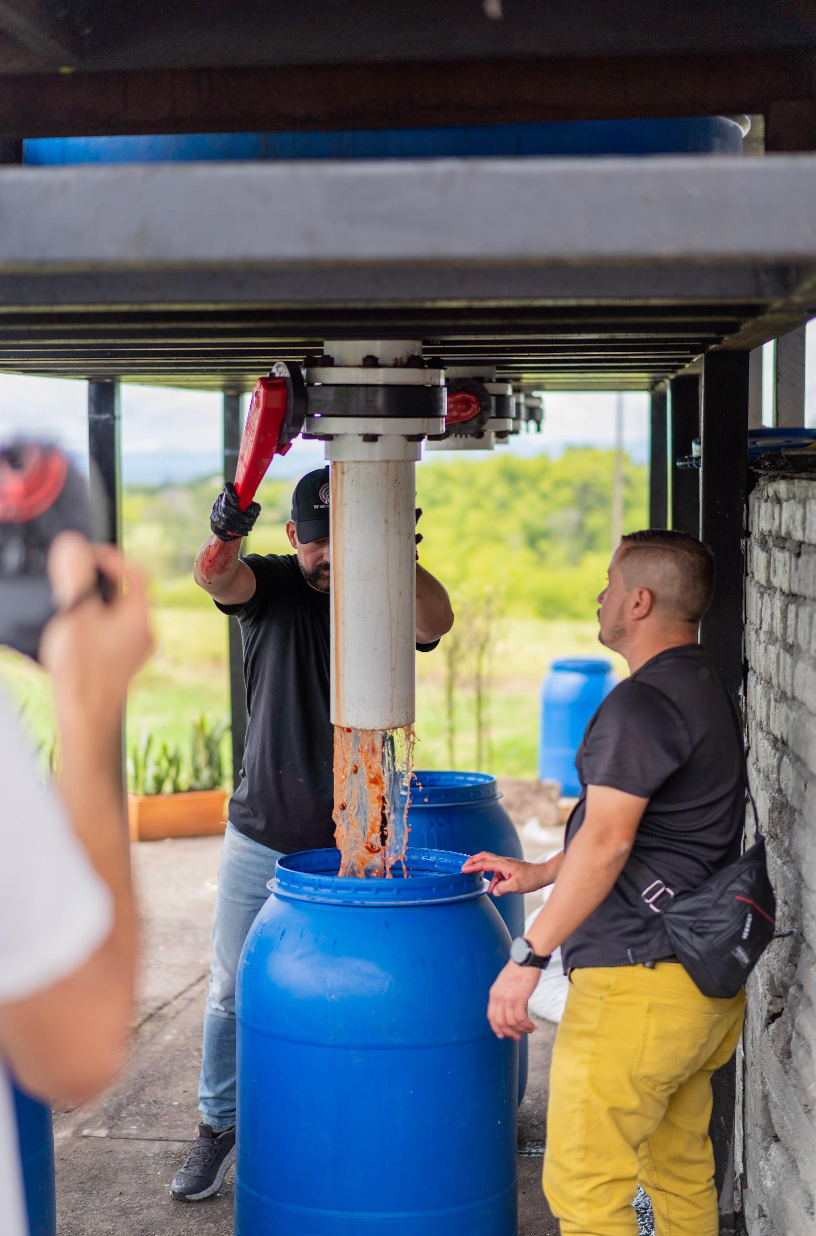 Edwin Noreña operating machinery above a blue fermentation chamber at Campo Hermoso