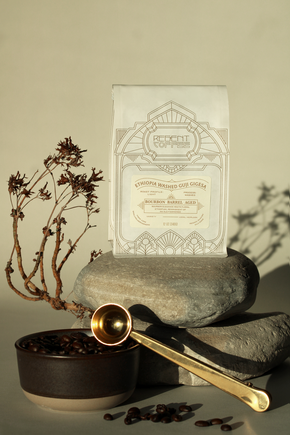 12 oz bag of Barrel Aged Ethiopia Washed Guji on a shaded rock above a bowl of coffee beans being scooped