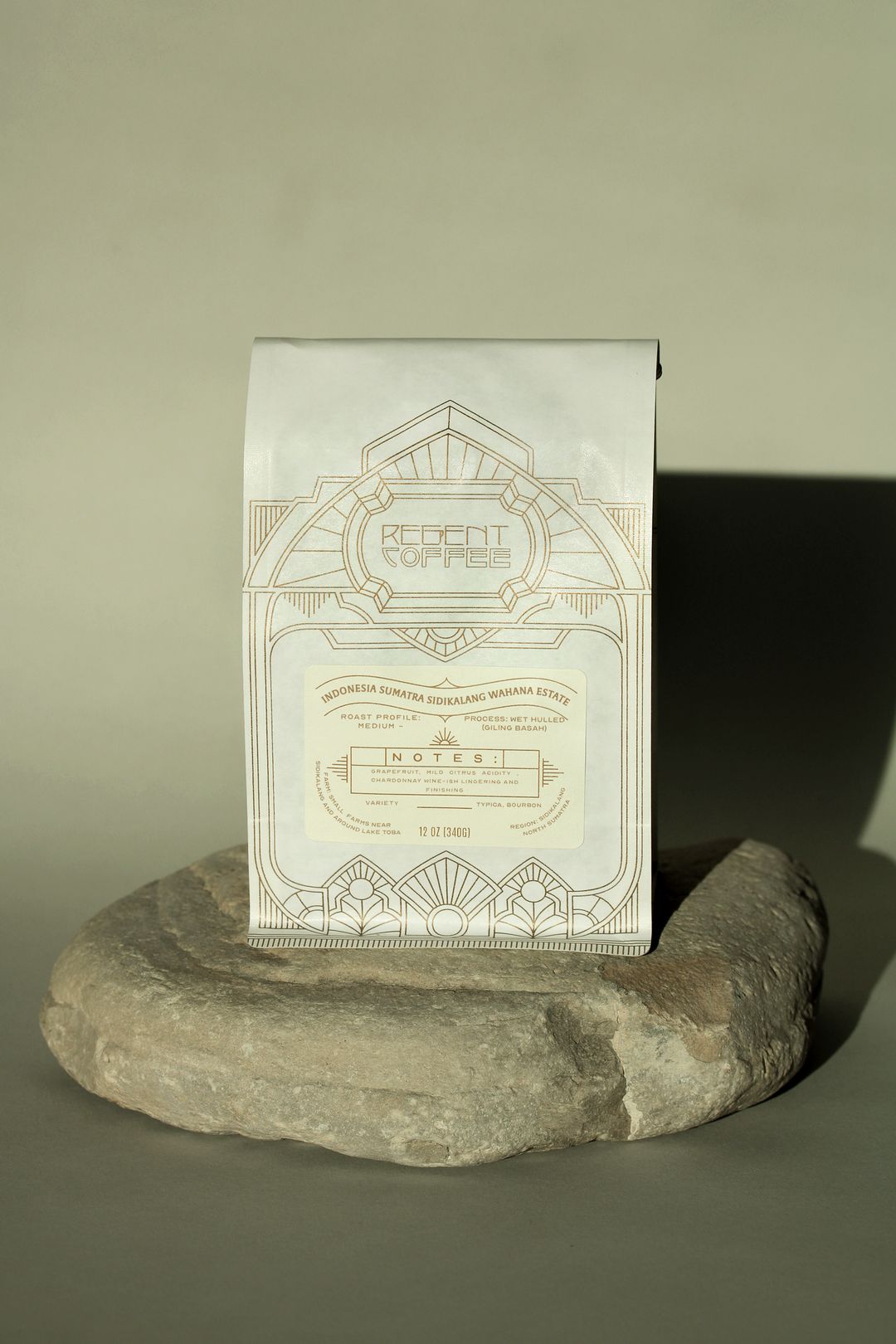 12 oz bag of Indonesia Sumatra Sidikalang Wahana Estate sitting on a rock casting a shadow