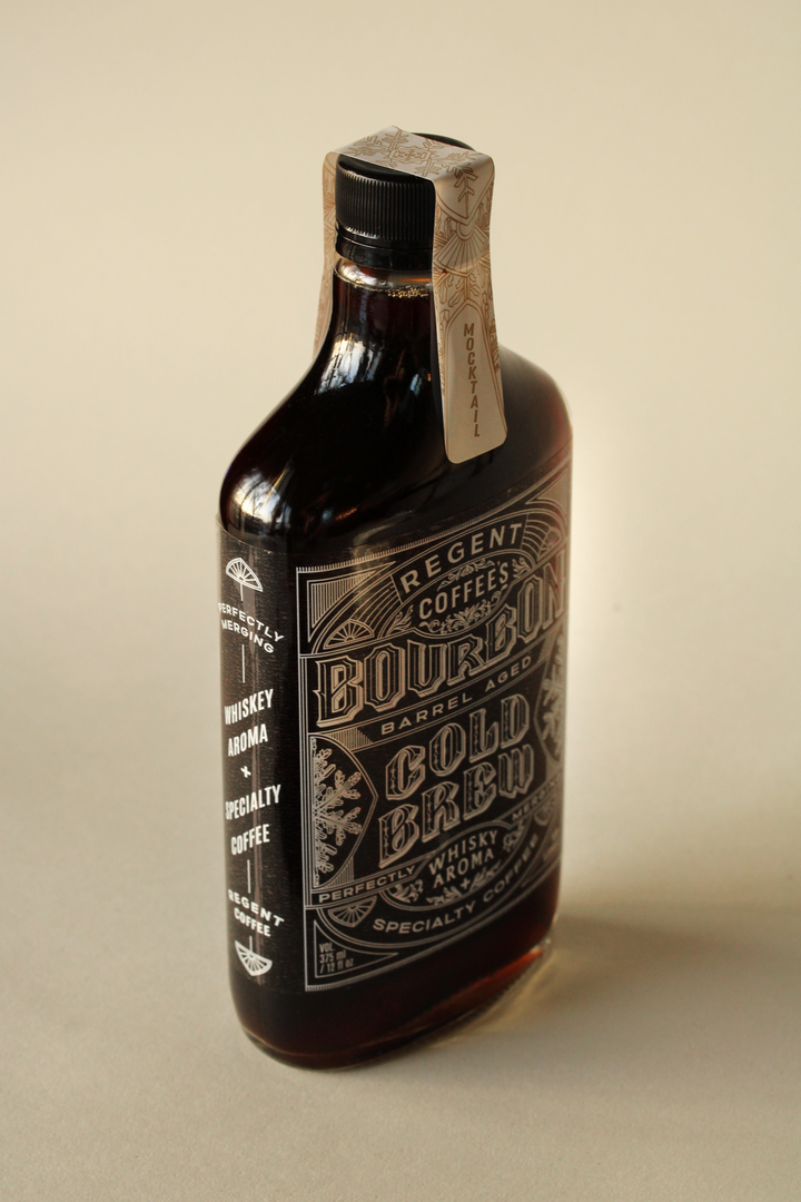 Bottle of Bourbon Gold Brew coffee with a wooden label on a beige background