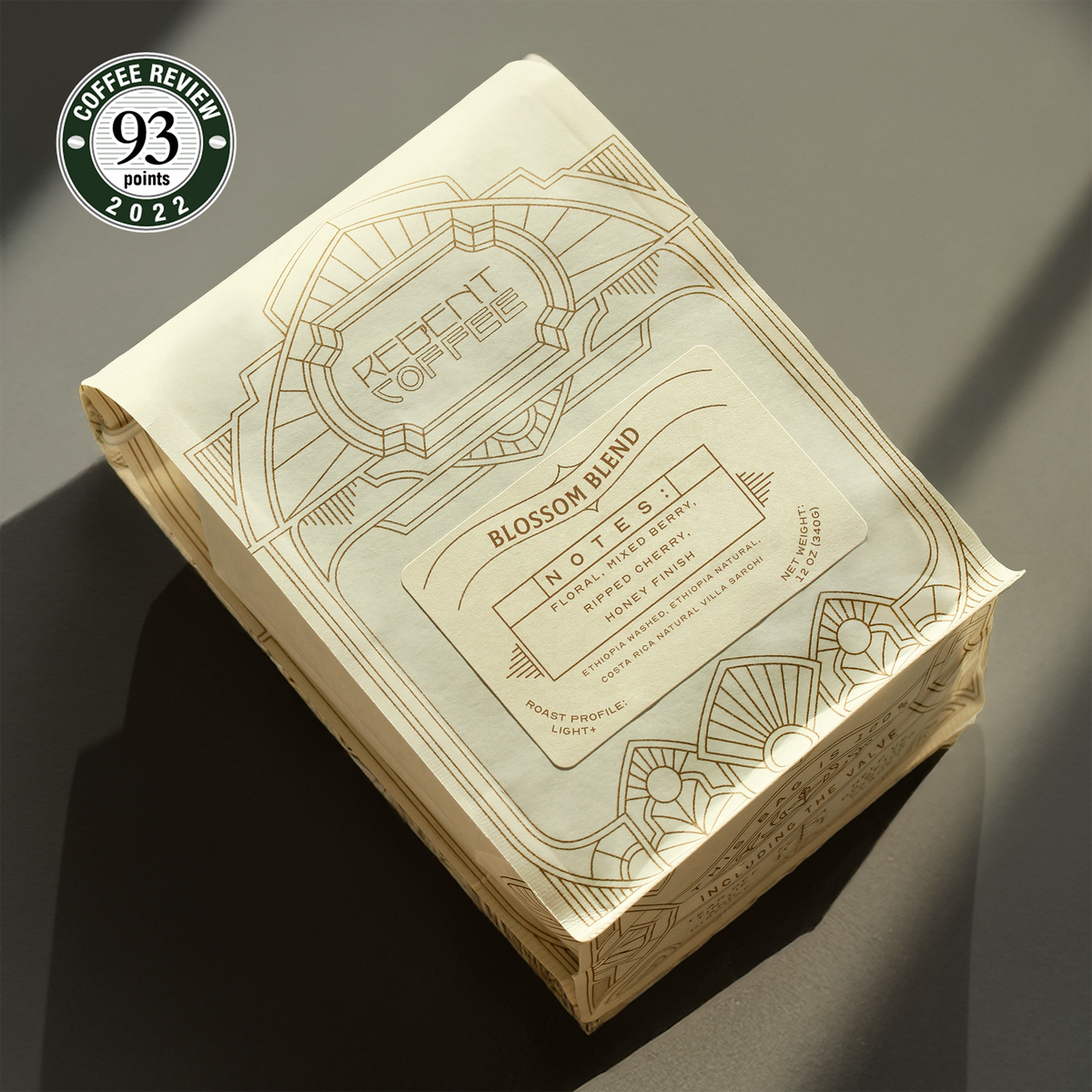 12 oz bag of Blossom Blend on a gray surface surrounded by shadows with a 93 scored Coffee Review 2022 Award emblem