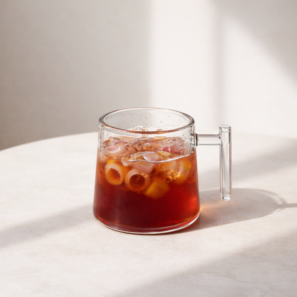 Clear glass mug with iced coffee on a white surface