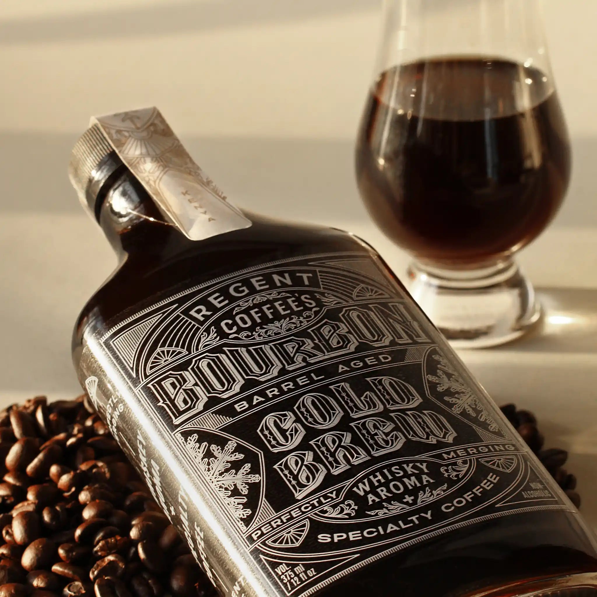 Regent Coffee's glass bottle ice cold brew coffee, atop a bed of dark roasted coffee beans