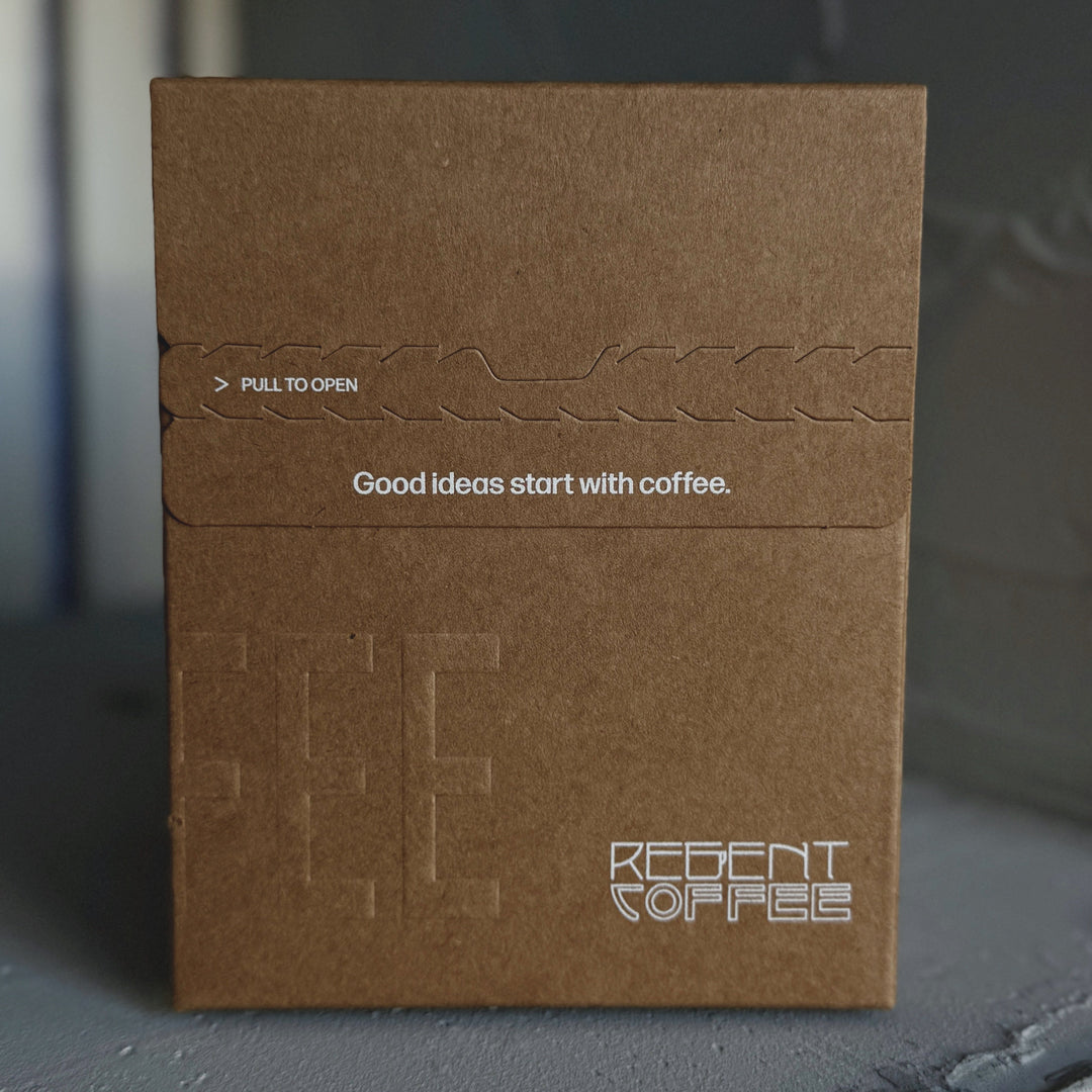 Brown coffee packaging with 'Recent Coffee' branding on a dark surface
