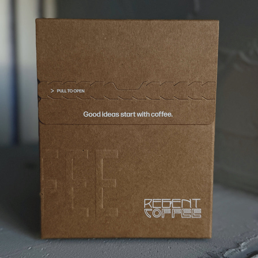 Brown coffee packaging with 'Recent Coffee' branding on a dark surface