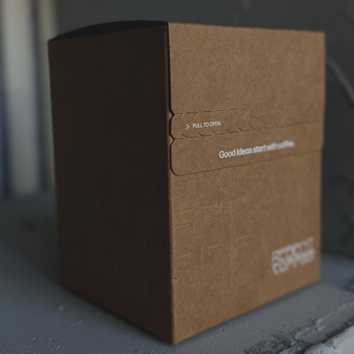 Brown cardboard box with text on a gray surface