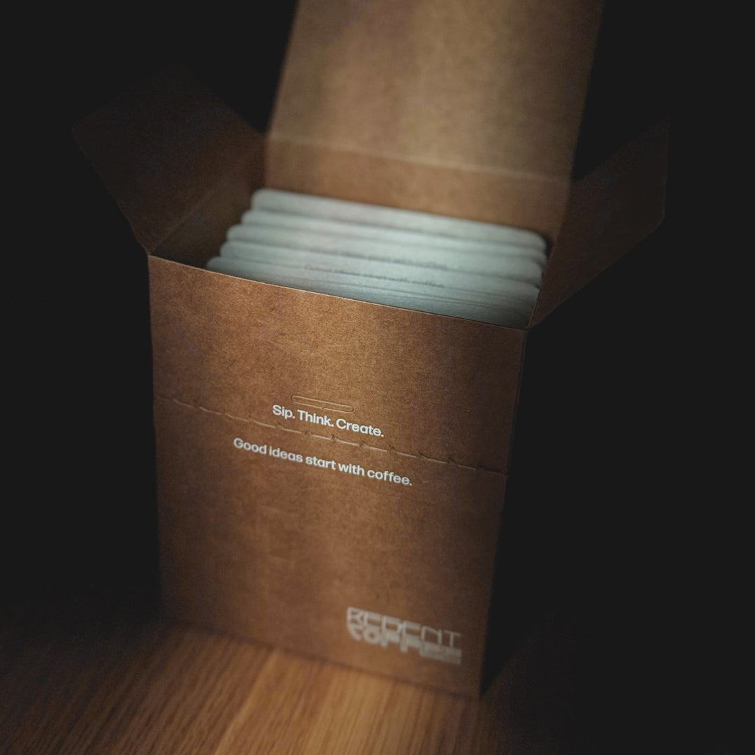 Brown coffee packaging with white coffee pods on a wooden surface