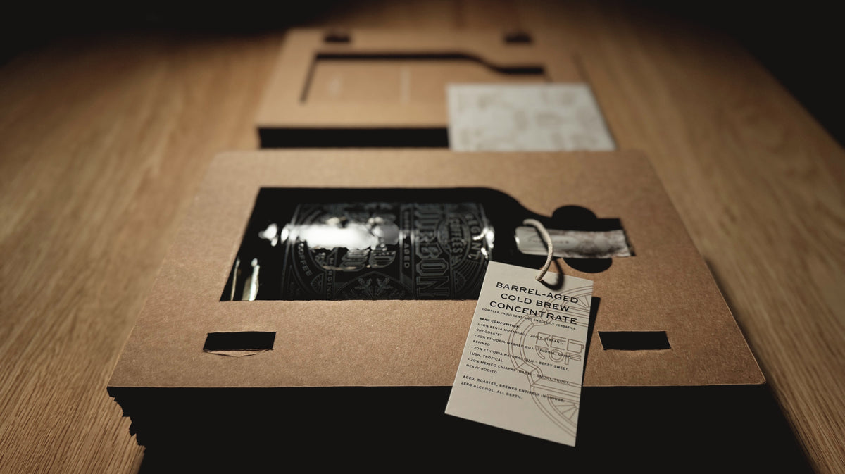 glass bottle in a cardboard sleeve with a tag on a wooden surface